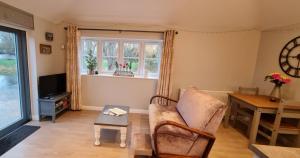 ein Wohnzimmer mit einem Sofa, einem Tisch und einem Fenster in der Unterkunft River Cottage in Stoke Ferry