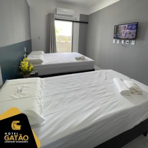 two beds in a hotel room with white sheets at HOTEL GATAO in Sobral