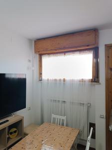um quarto com uma mesa, uma televisão e uma janela em la casina accogliente em Pisa