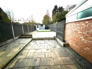 a patio with a fence and a brick building at Opple house in Coventry