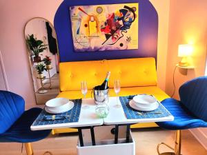 a dining room with a table and a yellow couch at Golden Art Studio in Saint-Germain-en-Laye