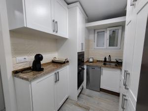 eine Küche mit weißen Schränken und einer Arbeitsplatte in der Unterkunft Apartamento Santa María in Arcos de la Frontera
