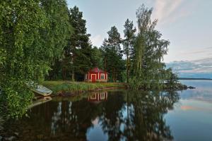 a small red cabin on the shore of a lake at Birgittagården in Falun