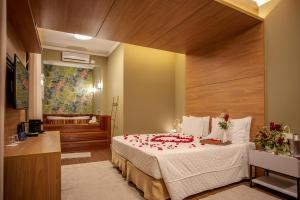 a bedroom with a bed with red rose petals on it at LS Villas Tranquillità in Águas de São Pedro