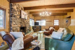 sala de estar con muebles de cuero y chimenea de piedra. en Steps to Lake Arrowhead Cabin with BBQ!, en Lake Arrowhead