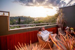 a man and woman sitting on a chair on a balcony at LS Villas Tranquillità in Águas de São Pedro +43 photos