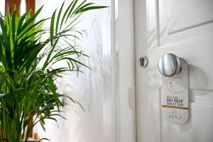 um sinal de porta numa porta branca com uma planta em Borgo Caridà - Green Family Holidays em Zaccanopoli