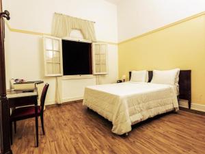 a bedroom with a bed and a desk and a window at Palace Hotel - Poços de Caldas in Poços de Caldas