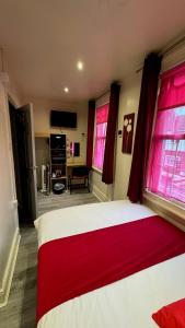 a bedroom with a large bed with red curtains at The Railway Sleeper Lodge in Colchester