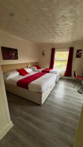 a bedroom with three beds with red pillows and a window at The Railway Sleeper Lodge in Colchester