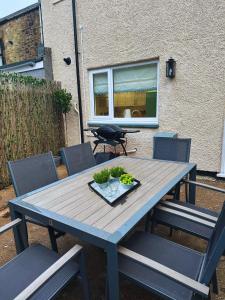 a wooden table with chairs and a bowl of greens on it at Avocet Cottage Amble in Amble