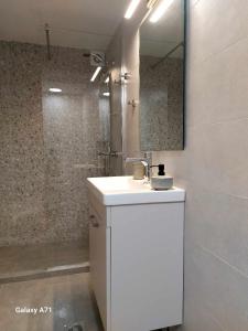 Baño blanco con lavabo y espejo en Square Apartments, en Tríkala