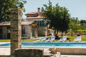 a group of lounge chairs next to a swimming pool at Villa Kanedolo in Momjan