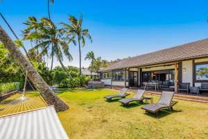 einen Außenblick auf ein Haus mit Stühlen und Palmen in der Unterkunft South Shore Paradise - 30-Night Minimum in Honolulu