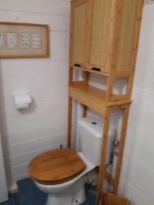 a bathroom with a toilet with a wooden shelf above it at Casefilo in Sainte-Luce