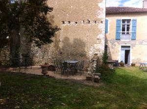 een tuin met een tafel en stoelen en een gebouw bij Ancien presbytere au coeur du village in Mauvezin