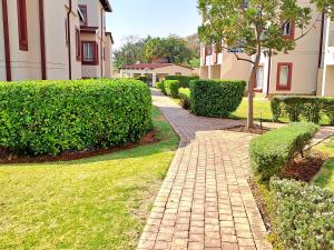a brick walkway in front of a building with bushes at Cozy Sparrow Hideaway in Sandton