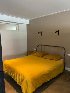 a bedroom with a bed with a yellow blanket at Stijlvol ruim studio-appartement nabij historisch centrum in Amersfoort