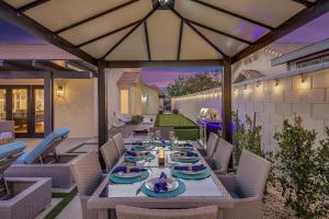 a patio with a table and chairs and an umbrella at THE Fun House FULL Arcade LUX backyard Sleeps 12 in Indio