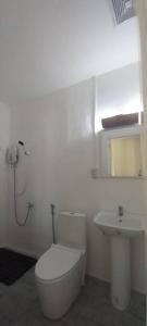 a white bathroom with a toilet and a sink at Bamboo Garden Tourist Inn in Carmen