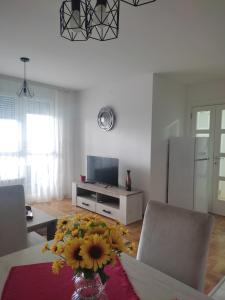 un salon avec une table et un vase de fleurs dans l'établissement Apartman Petra, à Niš