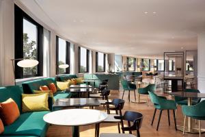 un ristorante con mobili e tavoli verdi e finestre di Sheraton Milan San Siro a Milano