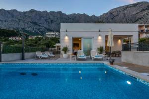 a villa with a swimming pool with mountains in the background at Family & Child friendly Villa Violet with Salt water pool in Makarska