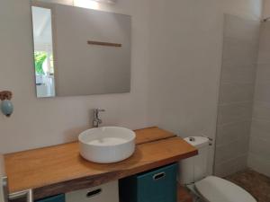 a bathroom with a sink and a toilet and a mirror at Cottages Les 3 Rochers - Vue sur mer in Terre-de-Bas