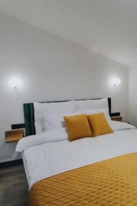 duże łóżko z białą pościelą i żółtymi poduszkami w obiekcie Apartamenty BIBLIO w Łodzi