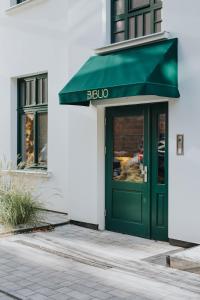 a green door of a store with a green awning at BIBLIO Apartamenty in Łódź
