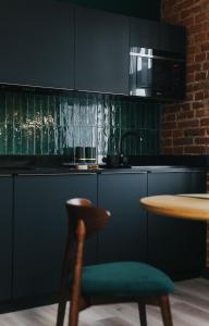 a kitchen with black cabinets and a table with a chair at BIBLIO Apartamenty in Łódź +145 photos