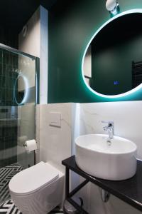 W łazience znajduje się umywalka, toaleta i lustro. w obiekcie Apartamenty BIBLIO w Łodzi