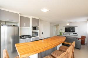 ピサーハスにあるEspaço amplo e confortável 3 Quartos, Churrasqueira, Cozinha completa, 180m da Praia, Wi-Fi, duas vagas de garagemのキッチン、リビングルーム(木製カウンタートップ付)