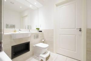 a white bathroom with a toilet and a sink at Greenwich O2 Apartment in London