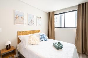 ピサーハスにあるEspaço amplo e confortável 3 Quartos, Churrasqueira, Cozinha completa, 180m da Praia, Wi-Fi, duas vagas de garagemの白いシーツと窓のあるベッドのある寝室