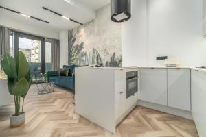 eine Küche mit weißen Schränken und ein Wohnzimmer in der Unterkunft Comfy Apartments 4-5th Floor Hanza Tower - Sauna & Pool in Stettin