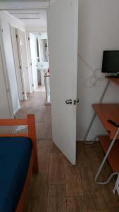 Habitación con puerta, mesa y escritorio. en Hospedaje Walgün en La Serena