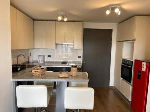 a kitchen with white cabinets and a counter with white stools at Nuevo, céntrico y acogedor dpto in Concepción