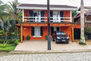 un coche aparcado frente a una casa naranja en Casa das Palmeiras, en Caraguatatuba