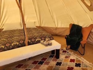 a bedroom with a bed and a chair and a rug at Two Little Piggies Glamping 