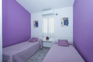 two beds in a room with purple walls at Villa Patri in Cala'n Porter +18 photos