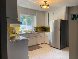 una cocina con nevera de acero inoxidable y armarios blancos en TheSunshine: Bright&Peaceful 2 Bdrm Character Home en Saskatoon