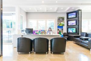 a woman sitting at a counter in a salon with chairs at Luz Hotel by Castelo Itaipava in Foz do Iguaçu