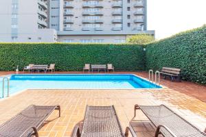 a swimming pool with two benches and a building at Luz Hotel by Castelo Itaipava in Foz do Iguaçu