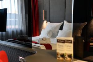 1 dormitorio con 1 cama con sábanas y almohadas blancas en Spa Hotel Ezeretz Blagoevgrad, en Blagoevgrad