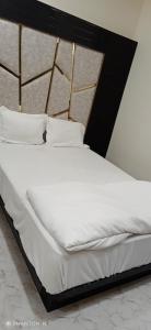 1 cama con marco negro y sábanas y almohadas blancas en Rk Hotal en Pusad