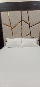 1 cama con 2 almohadas blancas y cabecero de madera en Rk Hotal en Pusad
