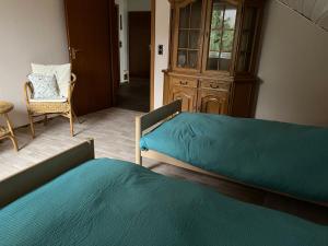 1 dormitorio con 2 camas, silla y armario en Unter den Wolken, en Winterberg