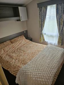 a bedroom with a bed with a comforter and a window at Littlesea Haven Weymouth in Weymouth