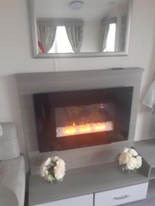 a fireplace in a living room with flowers on a table at Littlesea Haven Weymouth in Weymouth
